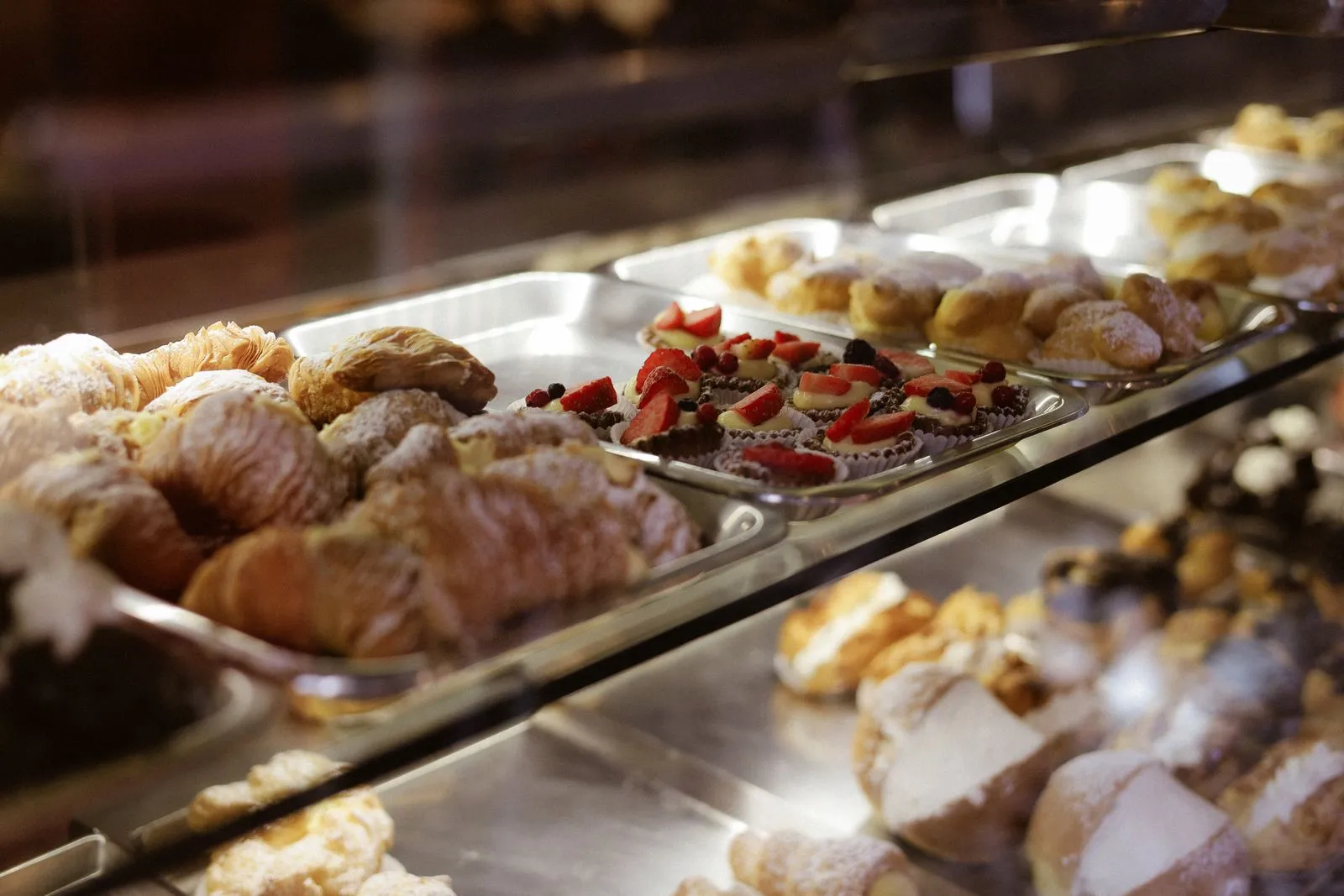 Bakery display case full of pastries with a QR code menu at the counter